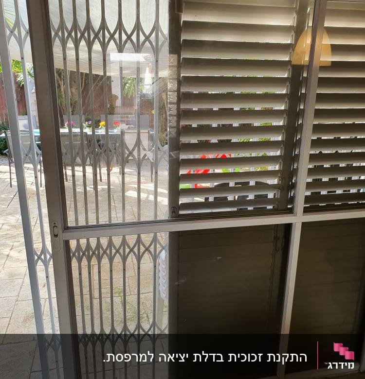 חלון זכוכית עם סורגים ותריסים פתוחים למחצה